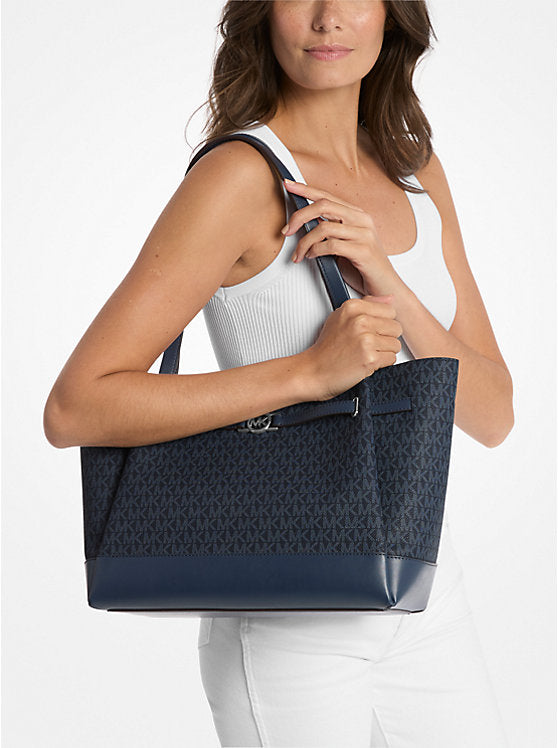 Michael Kors – Reed Large Navy Monogram Tote Shoulder Bag visas i användning av en modell.